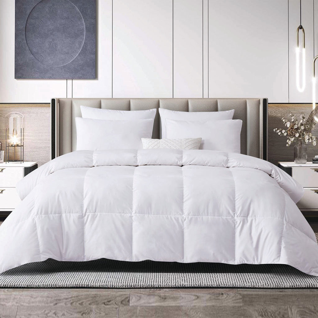 White comforter and pillows on a bed with wooden bench