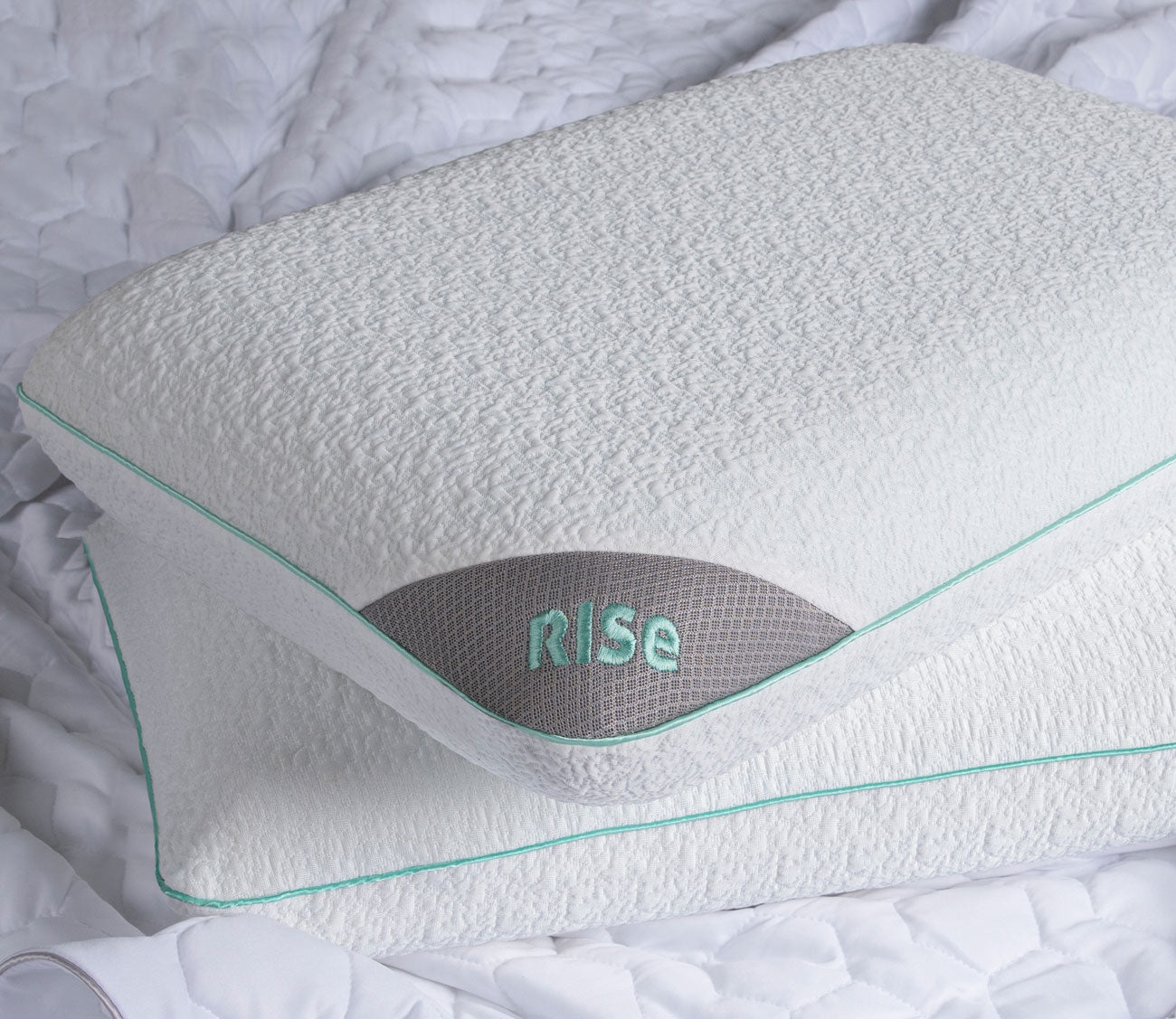 White pillow with 'RISE' branding on a textured surface