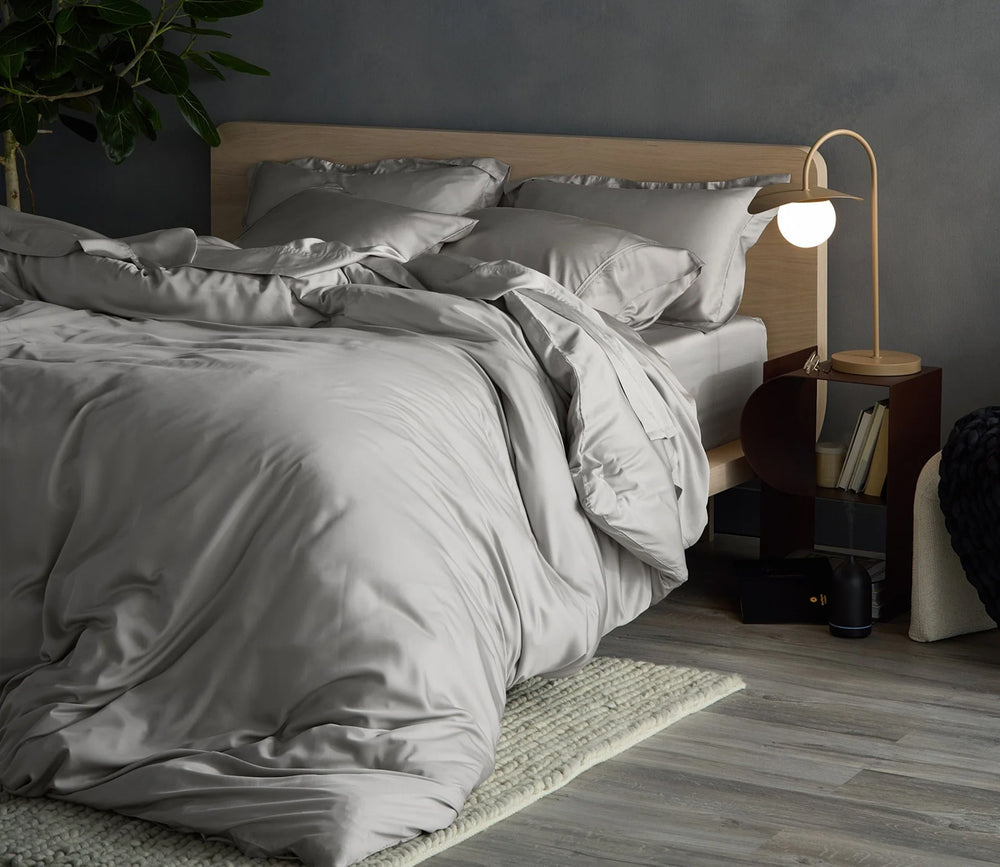 Neatly made bed with gray bedding in a bedroom setting.