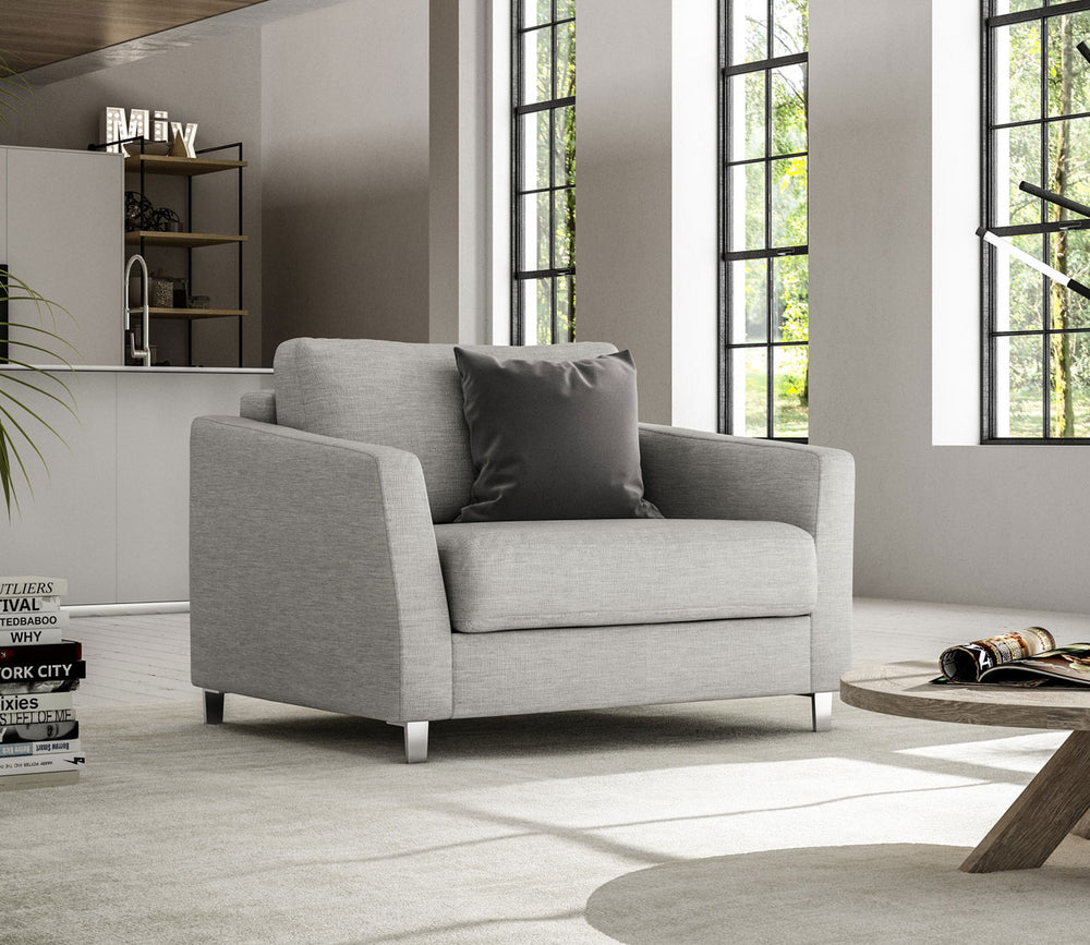 Gray armchair in a modern living room with large windows.