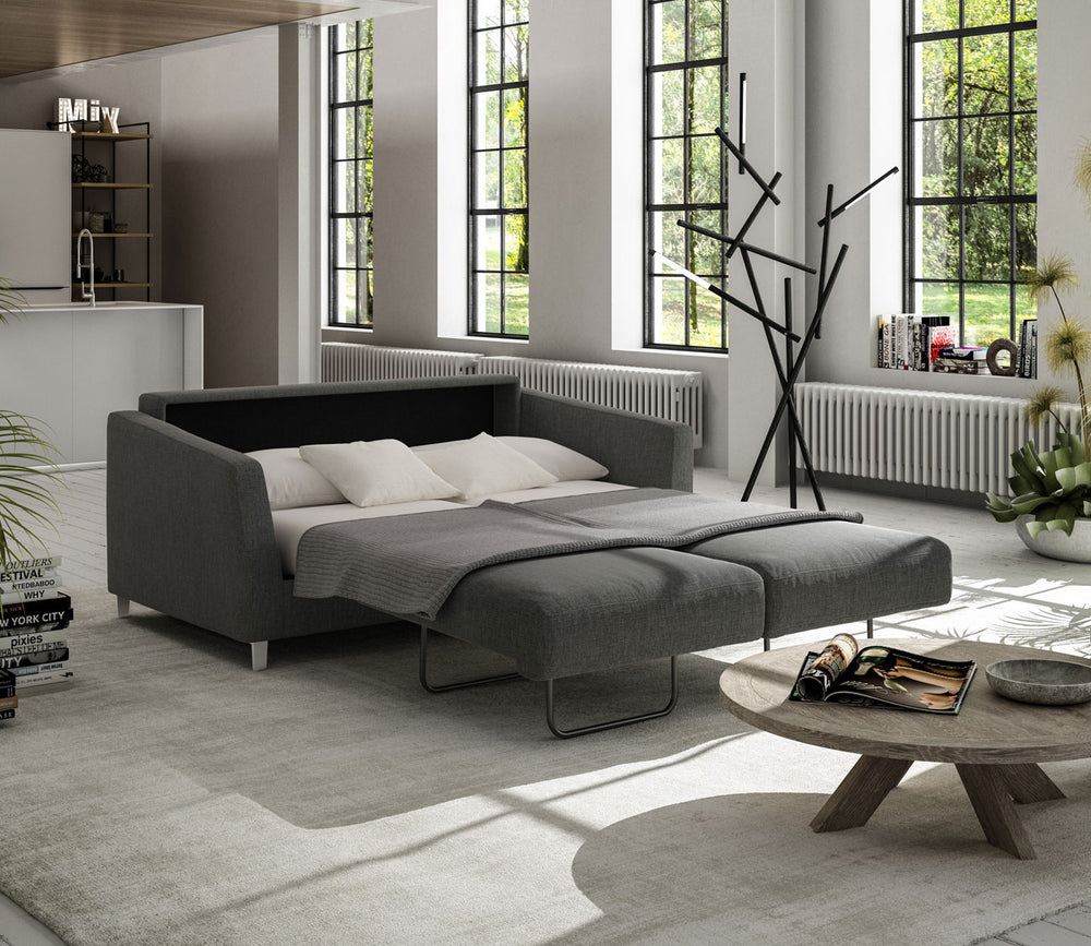 Modern living room with a gray sectional sofa, round coffee table, and large windows.