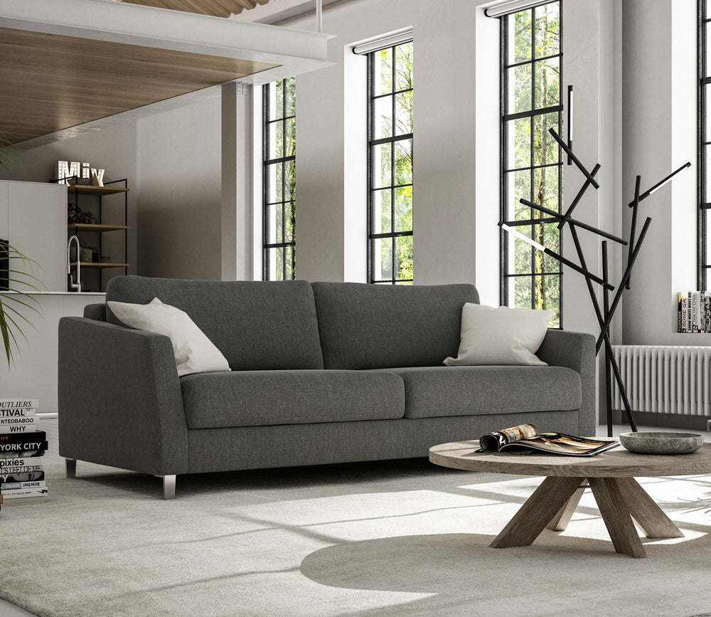 Gray sofa in a modern living room with large windows and a wooden coffee table.