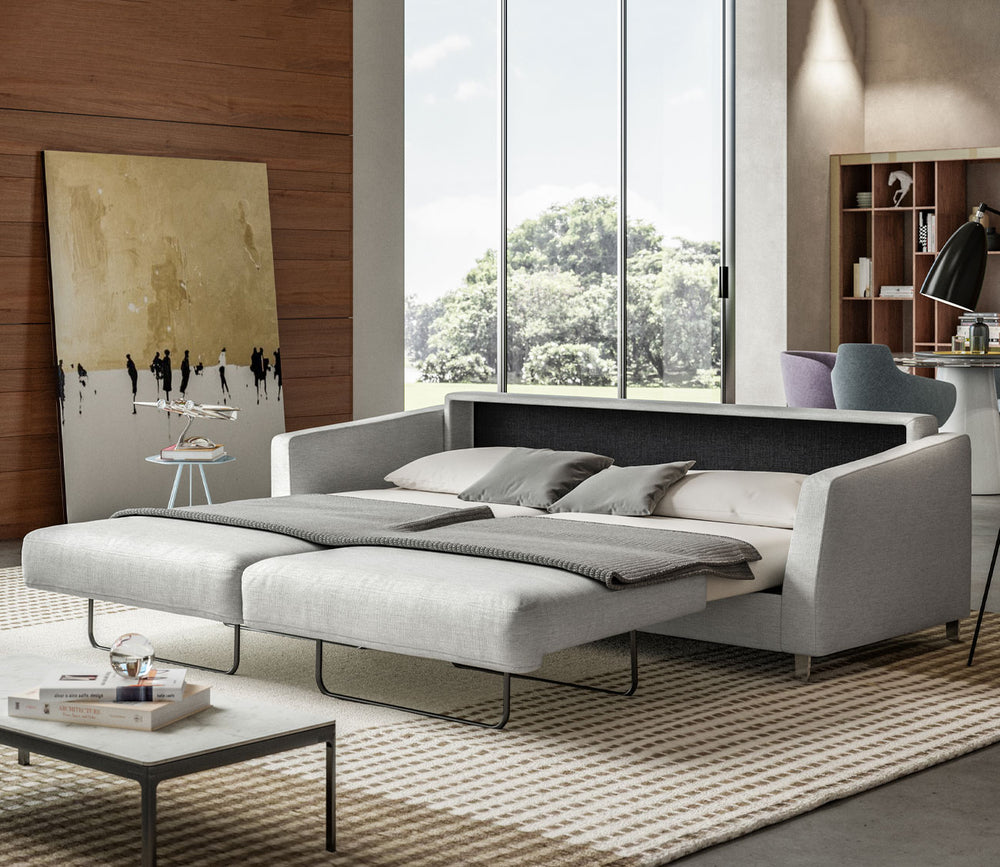 Modern living room with a sofa bed, coffee table, and large windows.
