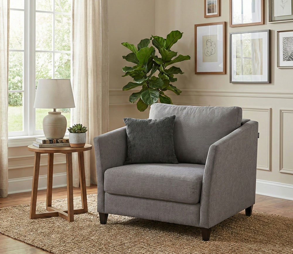Gray Naples Sleeper armchair in a living room with a plant, lamp, and side table.