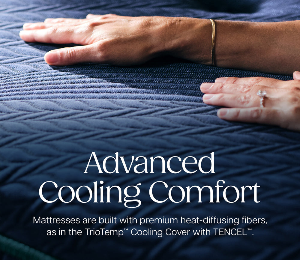 A close-up of a dark blue quilted mattress surface with two hands resting on it, overlaid with the text 'Advanced Cooling Comfort' and smaller descriptive copy about premium heat-diffusing fibers.