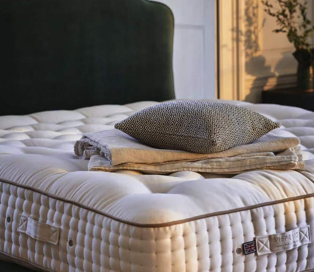 Vispring Masterpiece Superb Mattress with hand-tufted sleep surface styled with a folded throw and accent pillow.