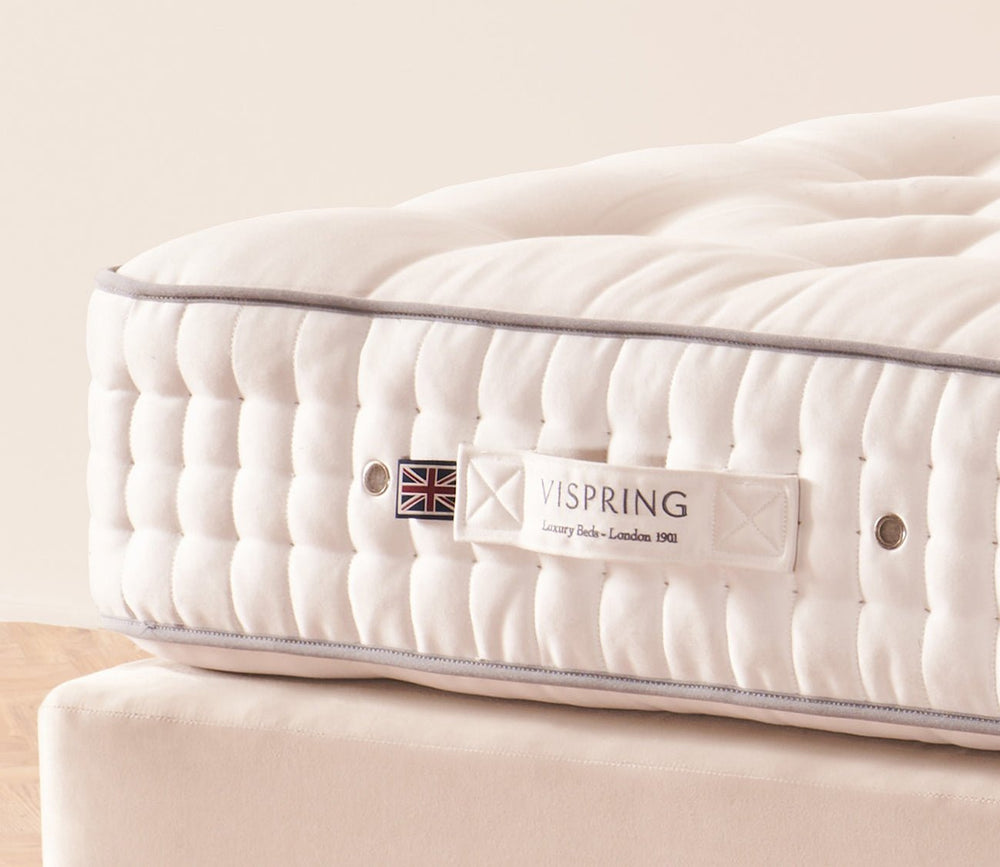 Close-up of the Vispring mattress side panel with hand-tufted detailing and signature label.