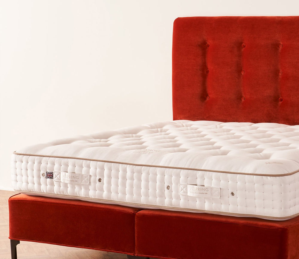 Vispring Signatory Superb Mattress on a red upholstered divan base with a hand-tufted sleep surface.