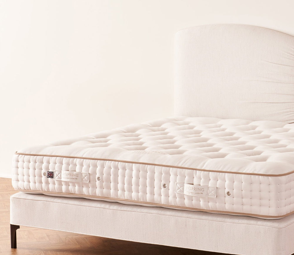 Vispring Sublime Superb Mattresson a cream upholstered divan base with a hand-tufted sleep surface.